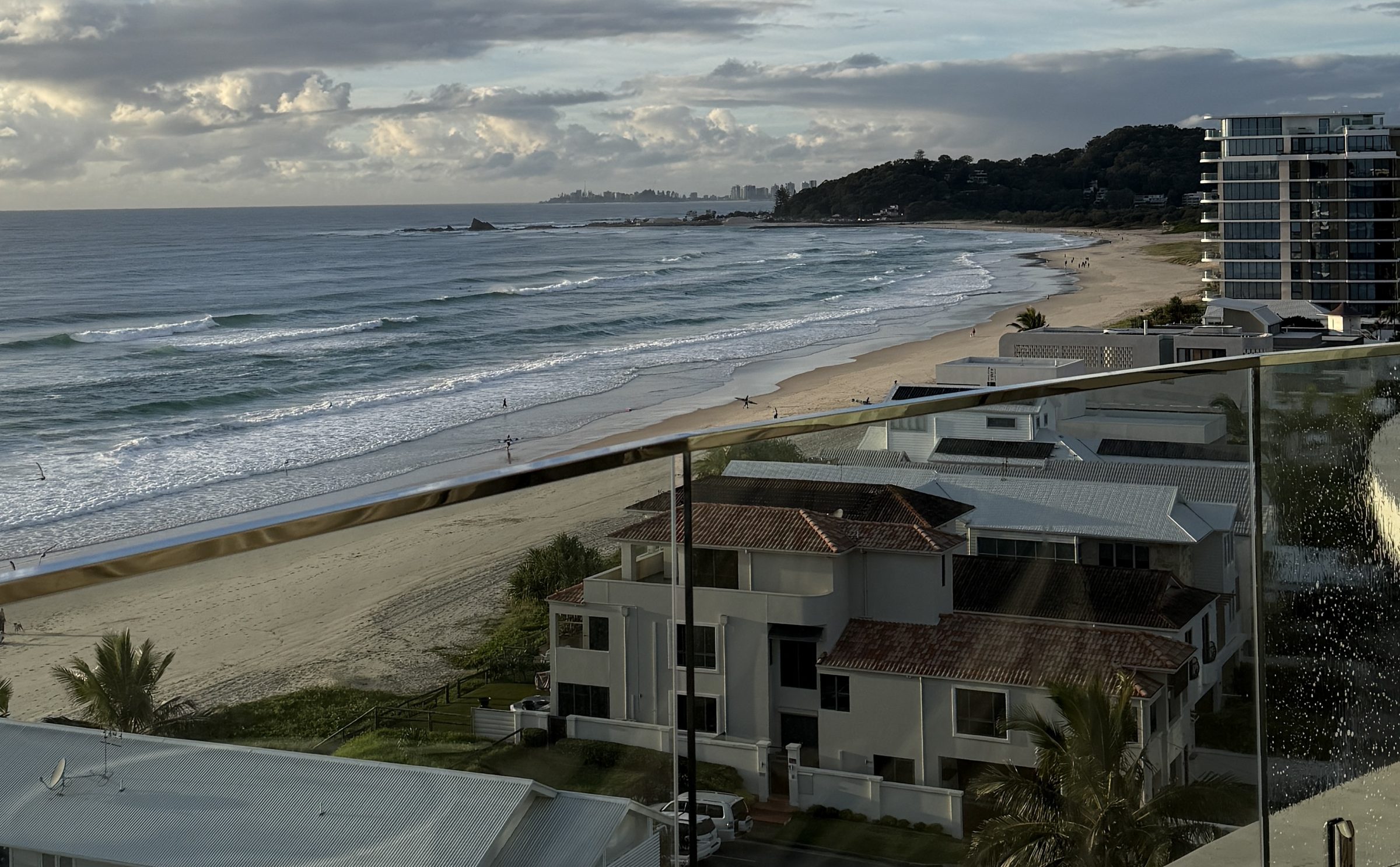 View along the Gold Coast beachfront from a high-rise balcony being cleaned, with a squeegee bucket in the foreground